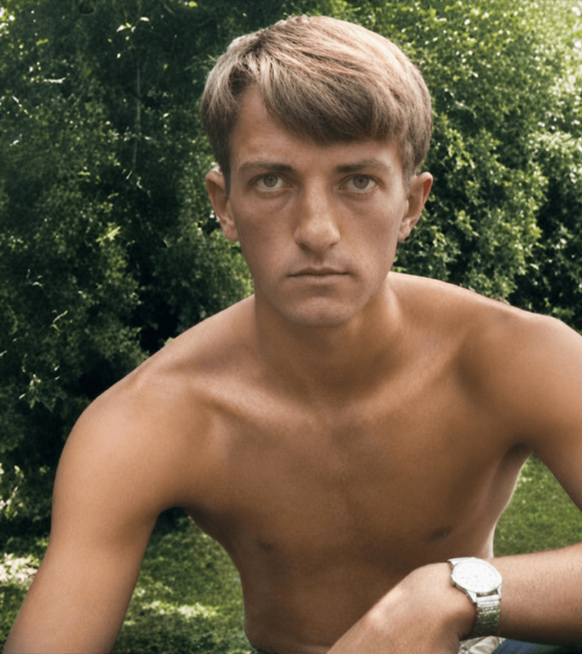 The same photograph restored: natural colour returned, detail in the eyes and watch recovered, the foliage behind him green again