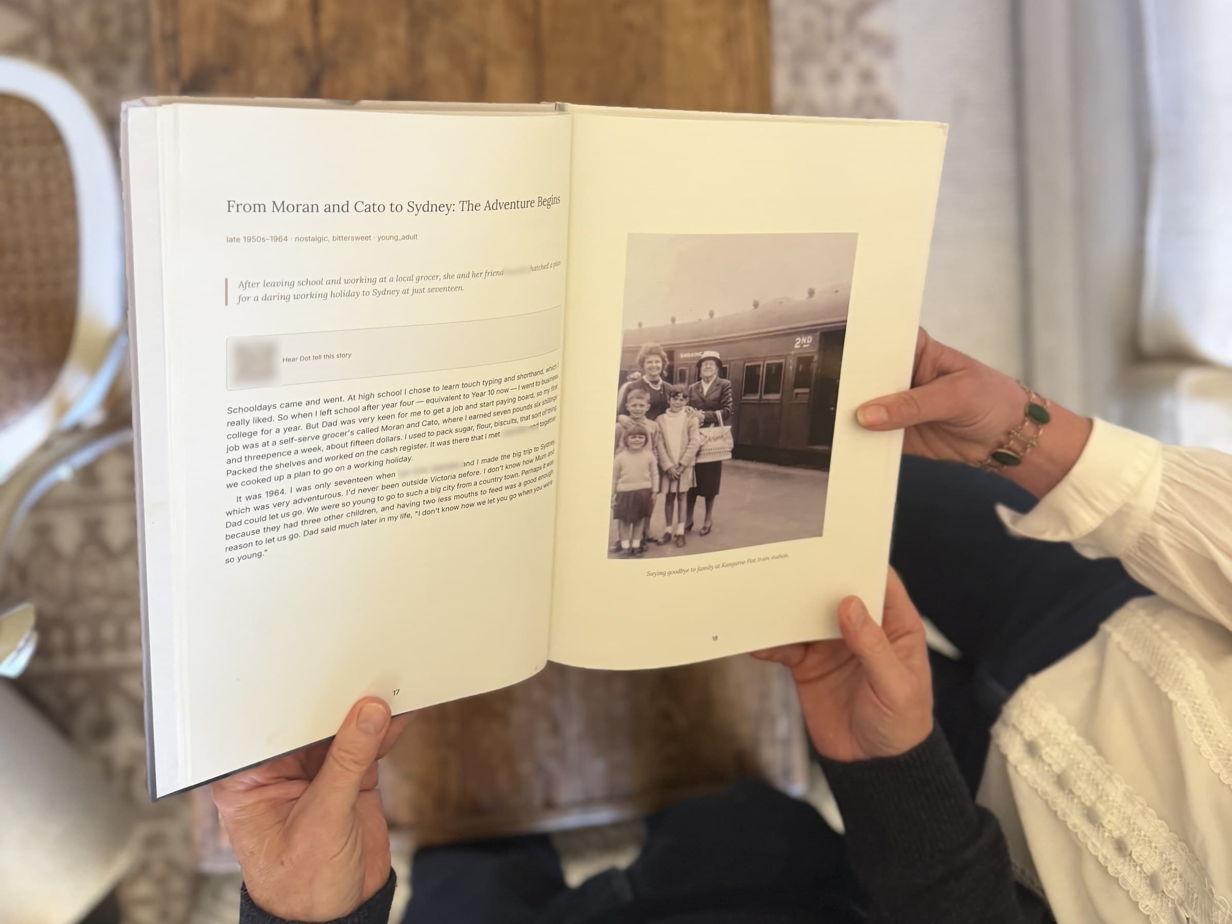 Hands holding a printed LifeLoom book open at a story, with a family photograph on the facing page