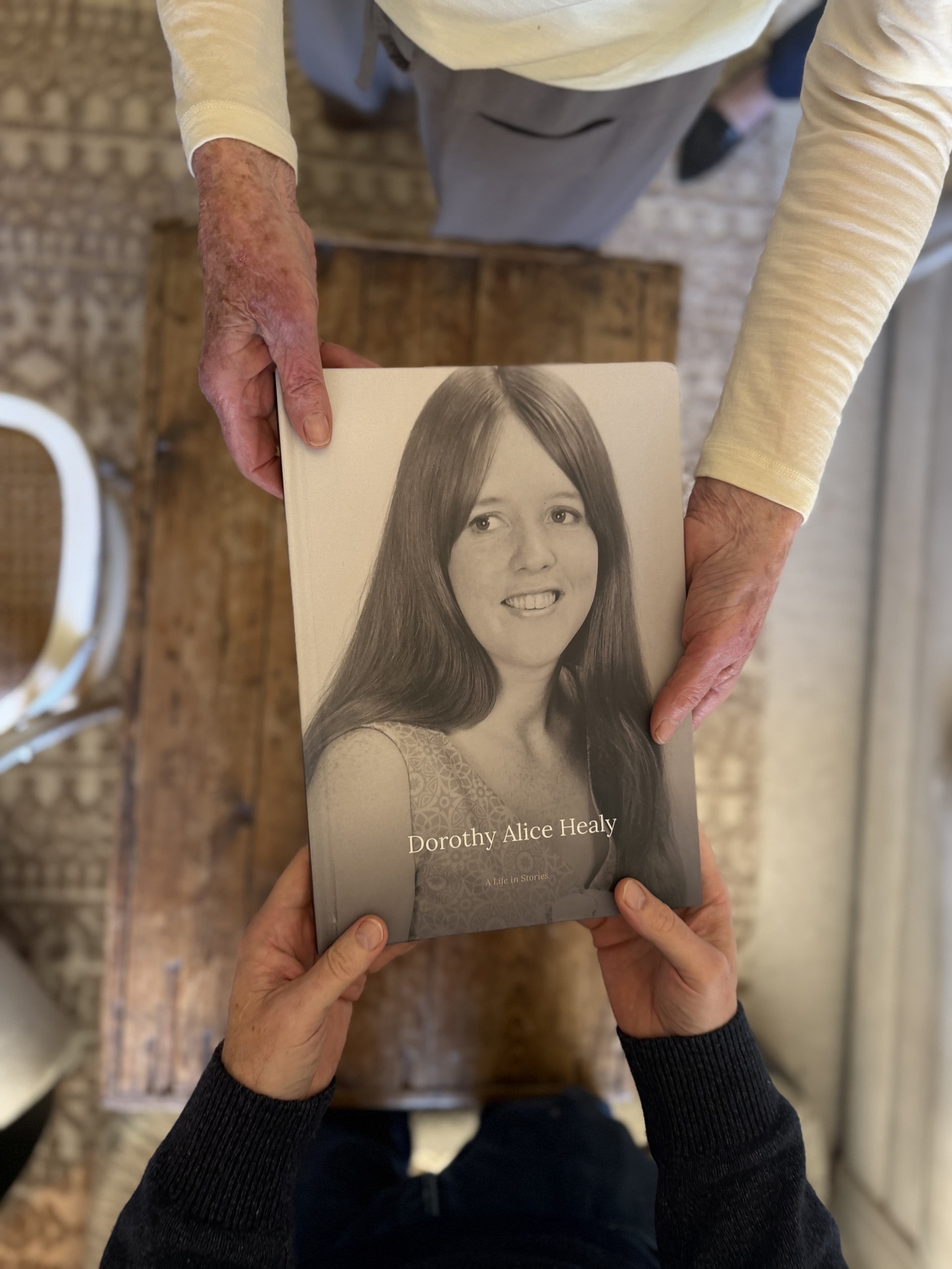Dorothy Alice Healy's printed LifeLoom book, A Life in Stories, being passed from one person's hands to another's